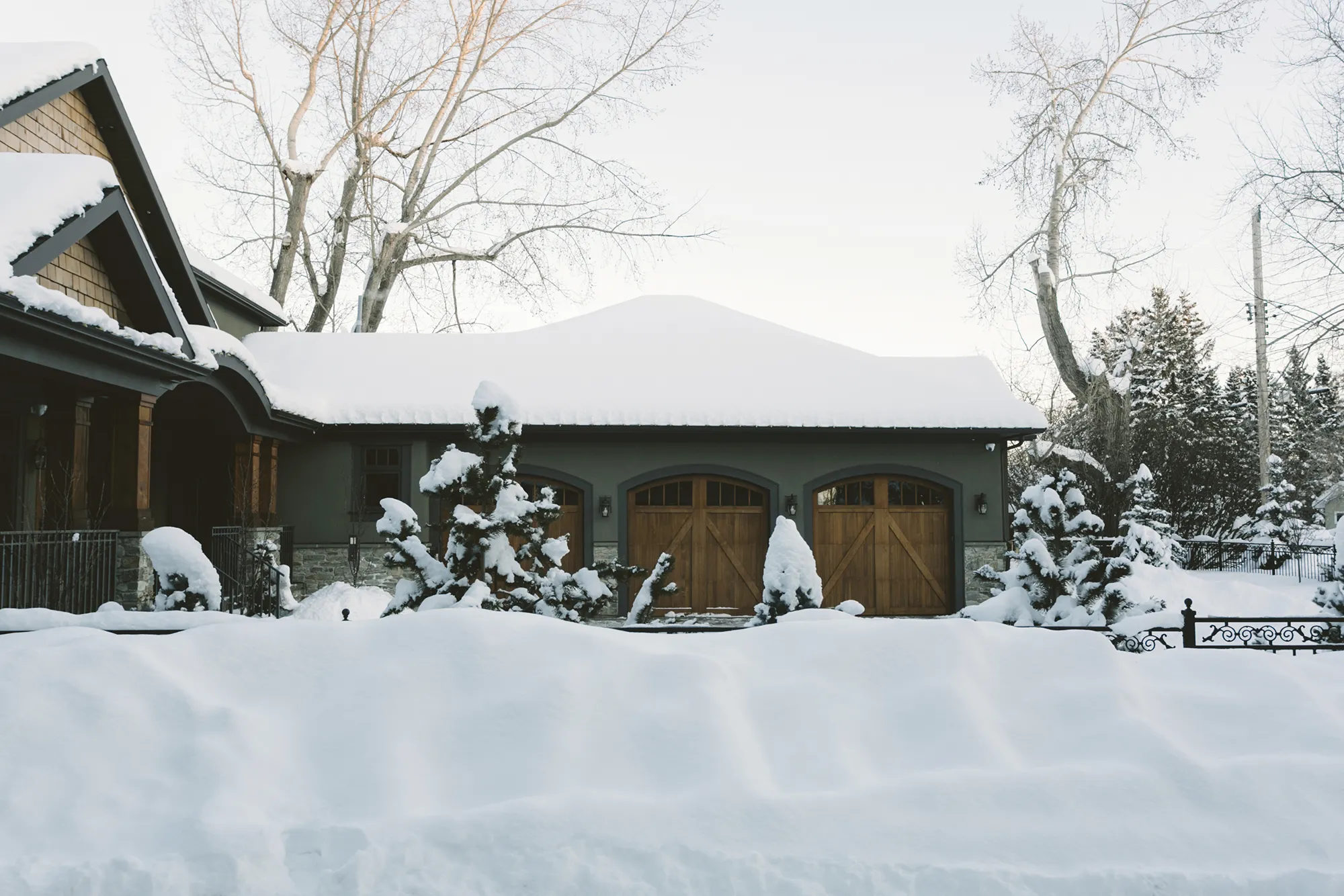 Maison en hiver avec accumulation importante de neige sur le toit, liée au service de déneigement de toiture.